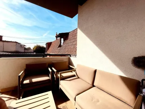 Namešten balkon sa garniturom za sedenje i pogledom na okolne krovove. - image 19