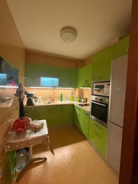 Manja kuhinja sa zelenim elementima i trpezarijskim stolom. - image 3