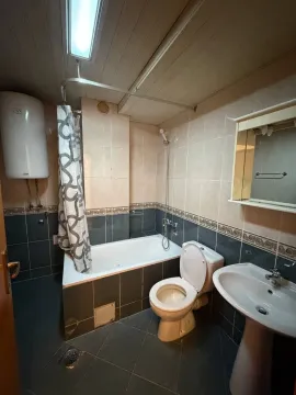 Smaller bathroom with a bathtub, washbasin, and toilet. - image 13