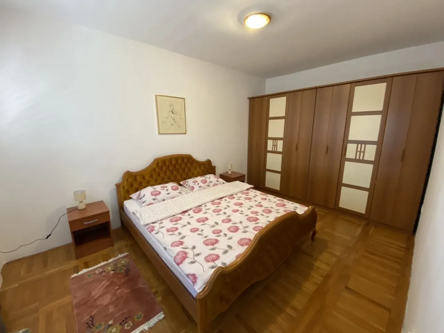 Bright bedroom featuring a large double bed and a wooden wardrobe.