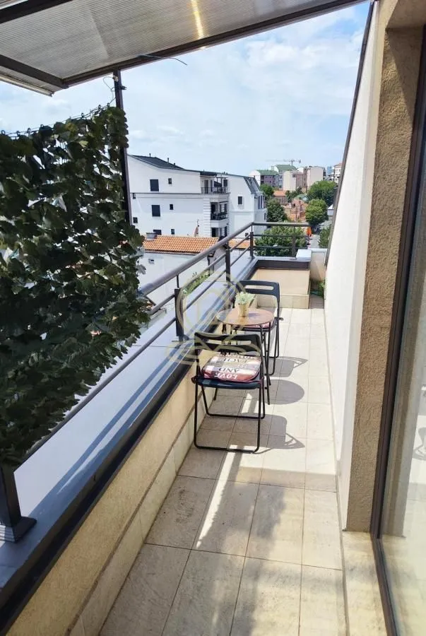 Natkriveni balkon sa garniturom za sedenje i pogledom na okolinu.