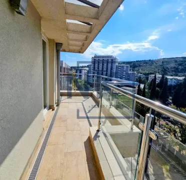 Spacious balcony with glass railing and city view. - image 12