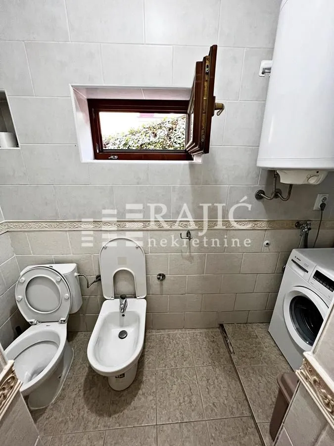 Small bathroom with toilet, bidet, washing machine, and water heater.