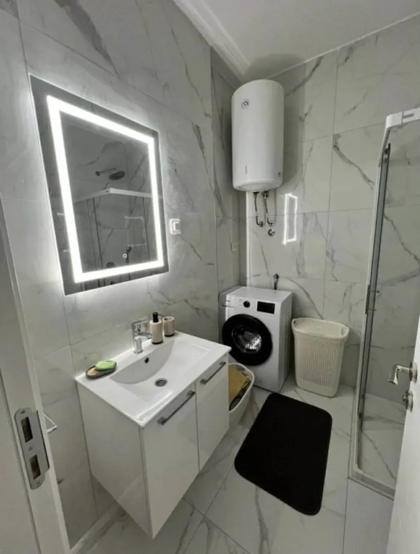 Moderne opremljeno kupatilo sa tuš kabinom, umivaonikom i veš mašinom.
