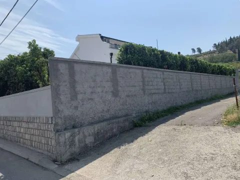 Concrete wall around a house yard with a green hedge. - image 3