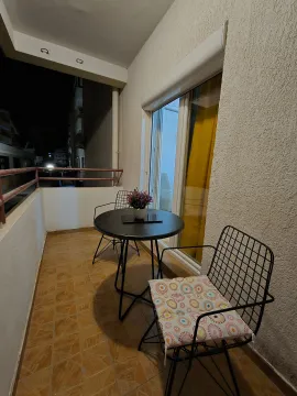 Furnished balcony with a table and two chairs in a night setting. - image 3