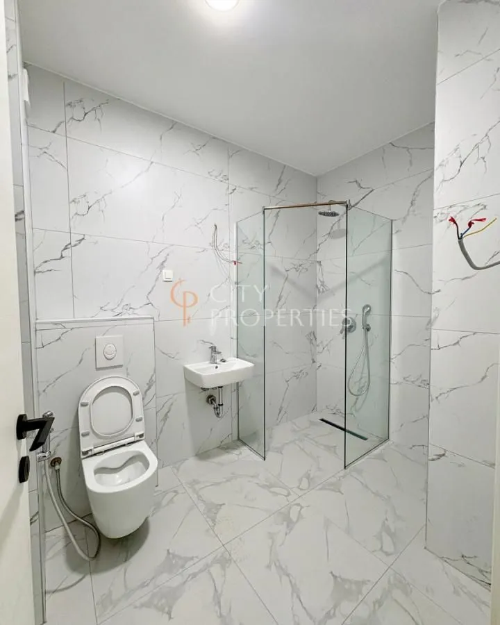 Newly equipped bathroom with a walk-in shower and marble-effect tiles.