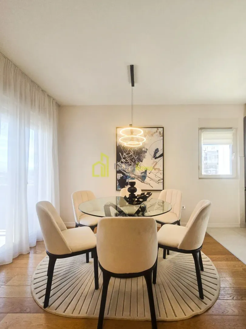 Dining area with a round glass table and modern chairs.