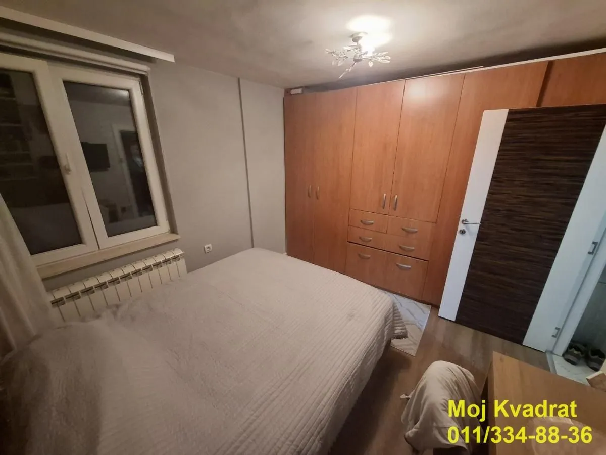 Spavaća soba sa bračnim krevetom i velikim drvenim ormarom.