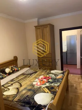 Bedroom with a double bed, wooden wardrobe, and a view into the kitchen. - image 2