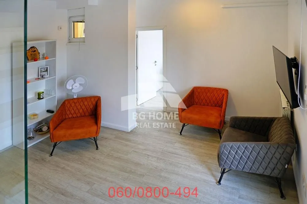 Small living room with armchairs, a shelving unit, and a television.