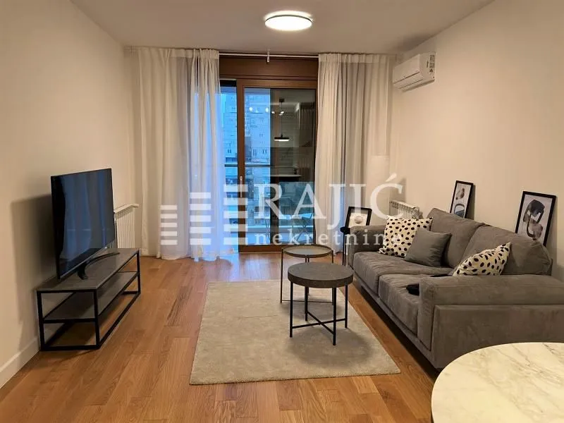 Living room with a sofa, TV console, and access to the terrace.