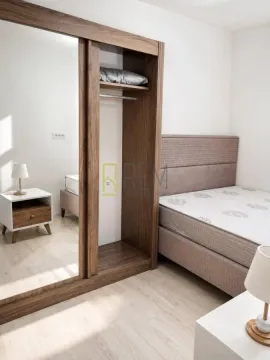 Bright bedroom with a double bed, a large wooden wardrobe with a mirror, and nightstands. - image 3