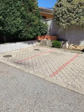Popločano parking mjesto u dvorištu okruženo zelenilom. - image 13