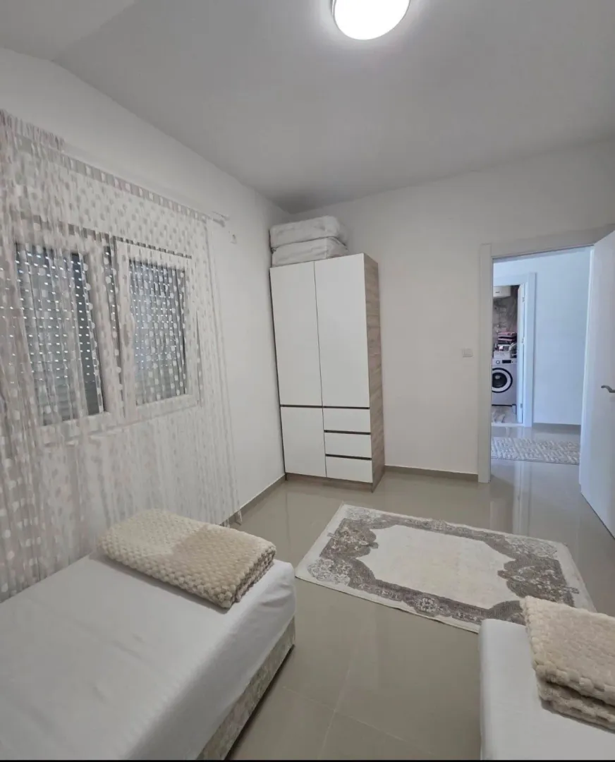 Svijetla spavaća soba sa krevetom, ormarom i prozorom.