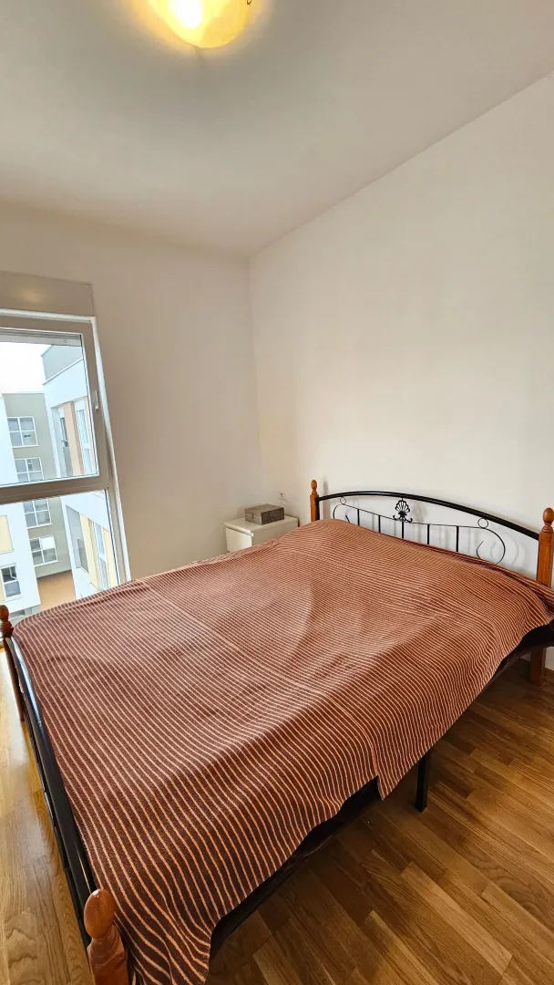 Bedroom with a double bed and a window overlooking a building.
