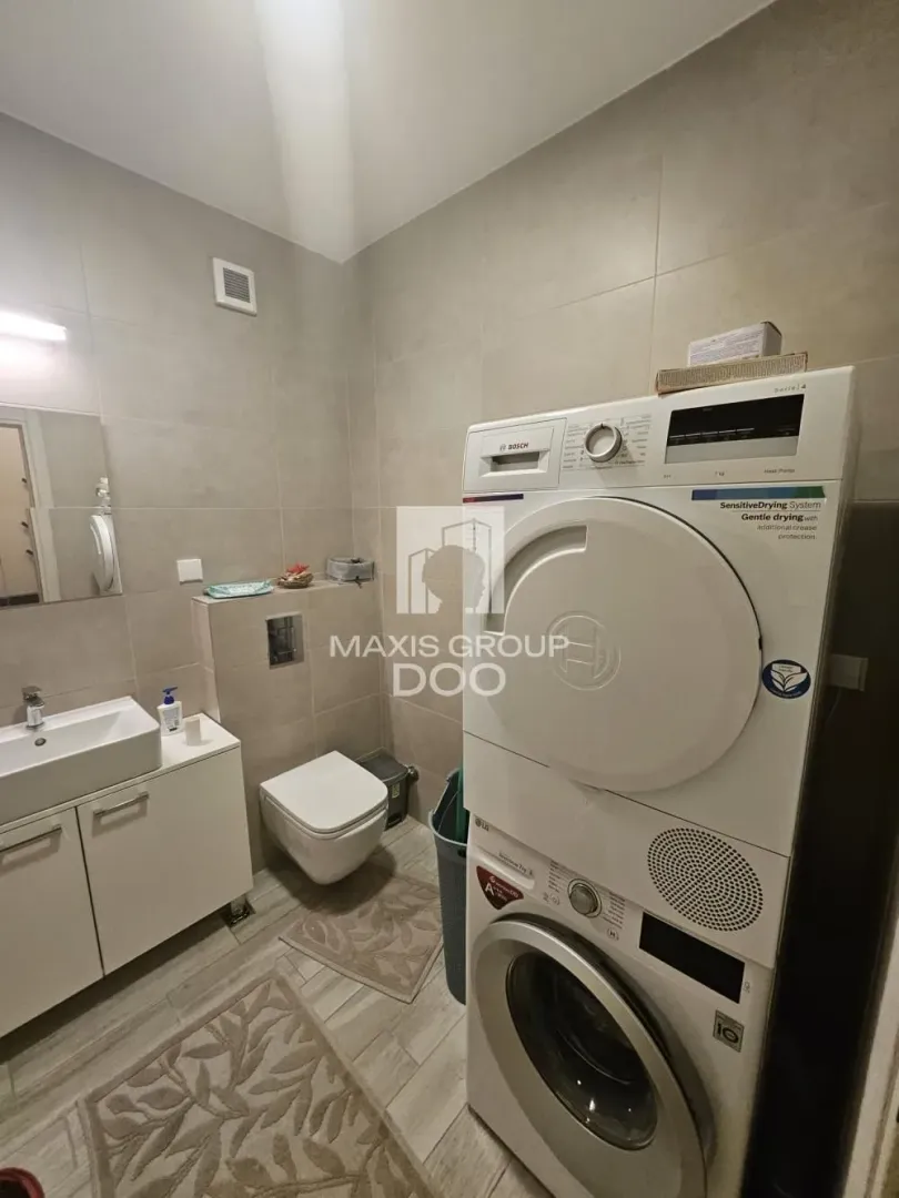 Moderno kupatilo sa veš mašinom, sušilicom i ugradnim umivaonikom.