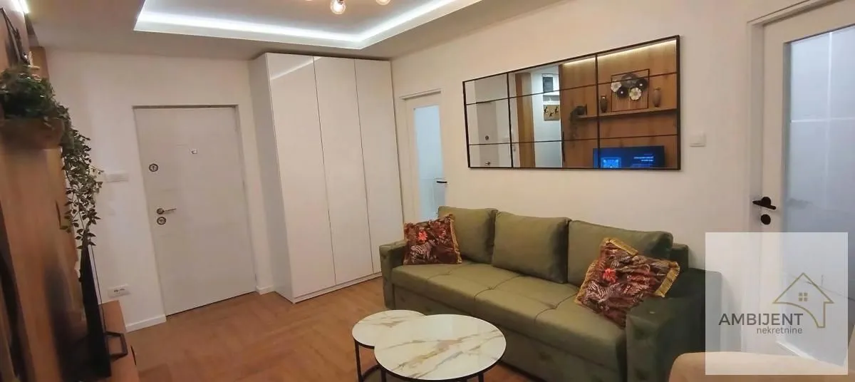 Living room with a green sofa, coffee tables, and a large wall mirror.