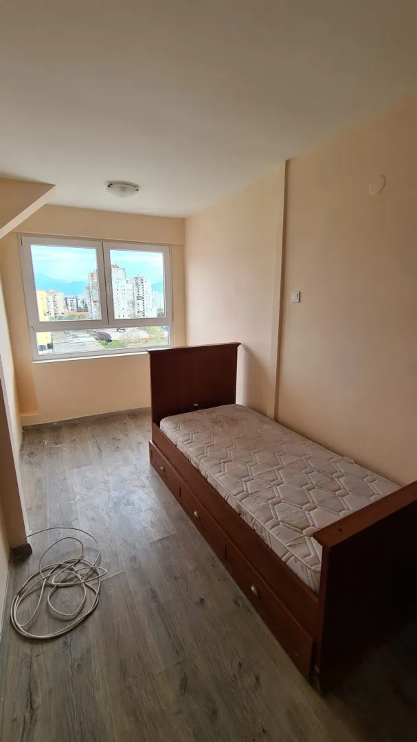 Small bedroom with a wooden bed and a city view.