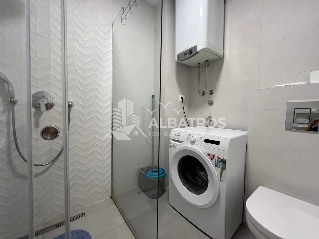 Modern bathroom equipped with a walk-in shower, washing machine, and water heater.