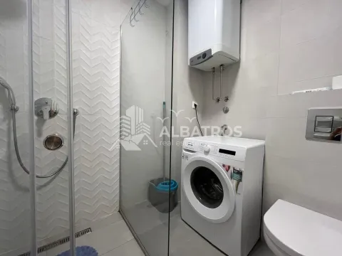 Modern bathroom equipped with a walk-in shower, washing machine, and water heater. - image 12