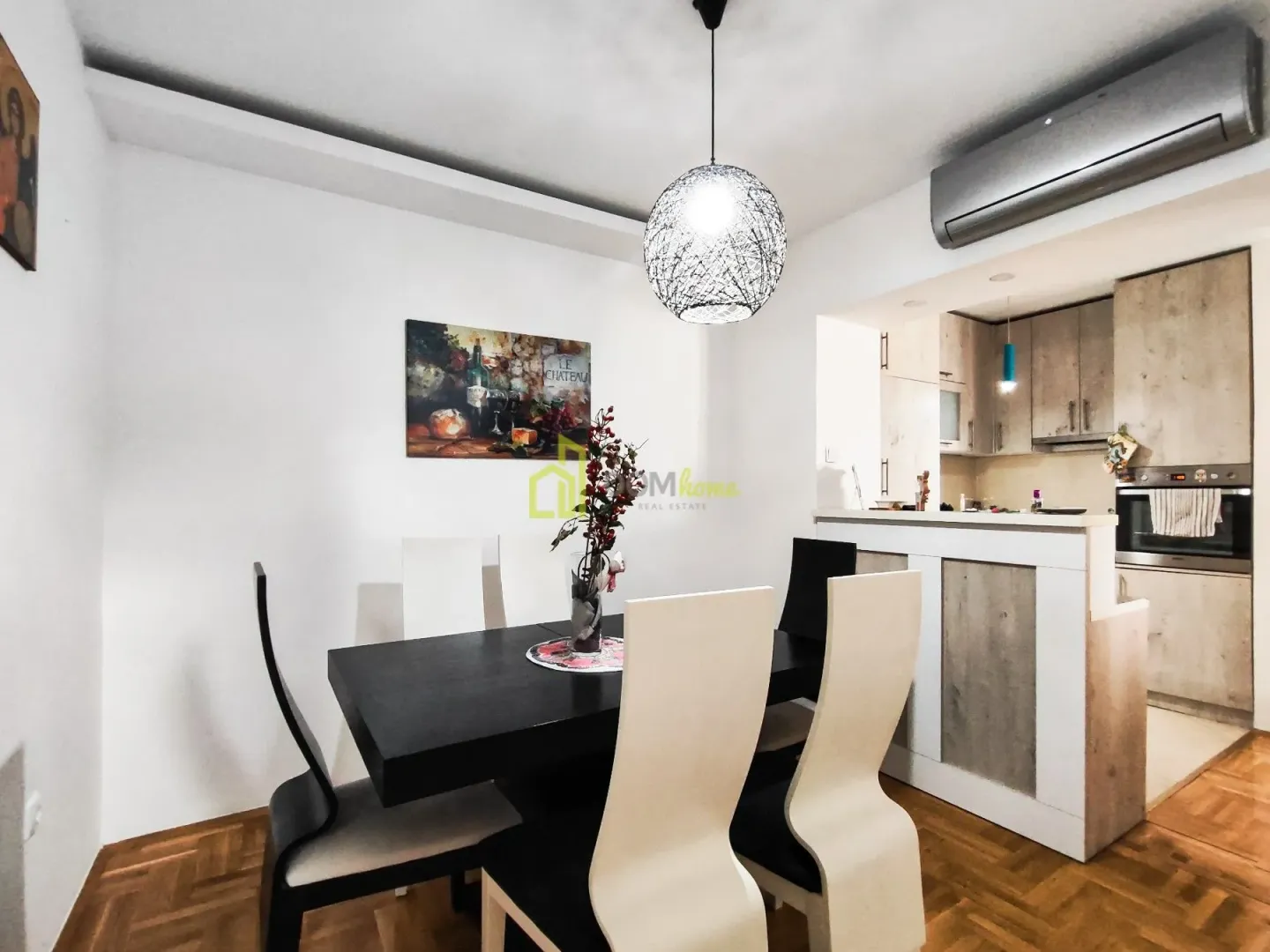 Dining area with a black table and white and black chairs, connected to the kitchen.