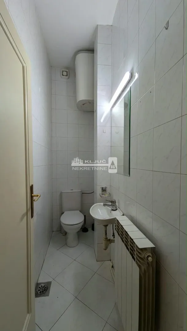 Small bathroom with white tiles, a washbasin, and a toilet.