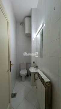 Small bathroom with white tiles, a washbasin, and a toilet. - image 8