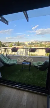 Namešten balkon sa veštačkom travom i pogledom na grad. - image 12