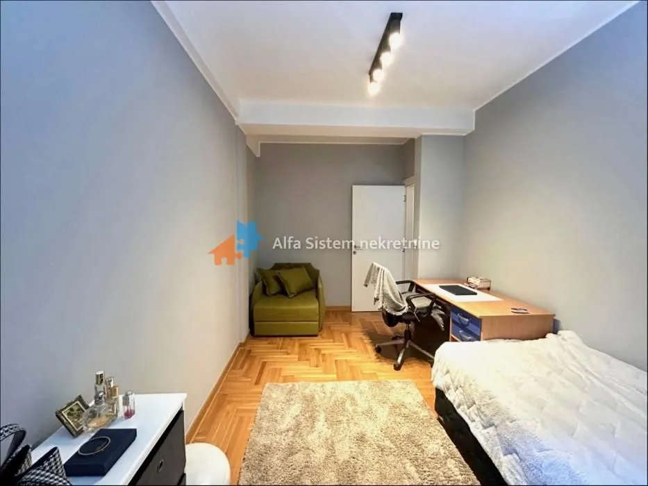 Furnished bedroom with a bed, desk, and armchair.