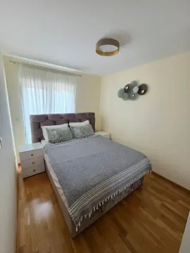 Uređena spavaća soba sa bračnim krevetom, noćnim stočićima i dekoracijom na zidu. - image 10
