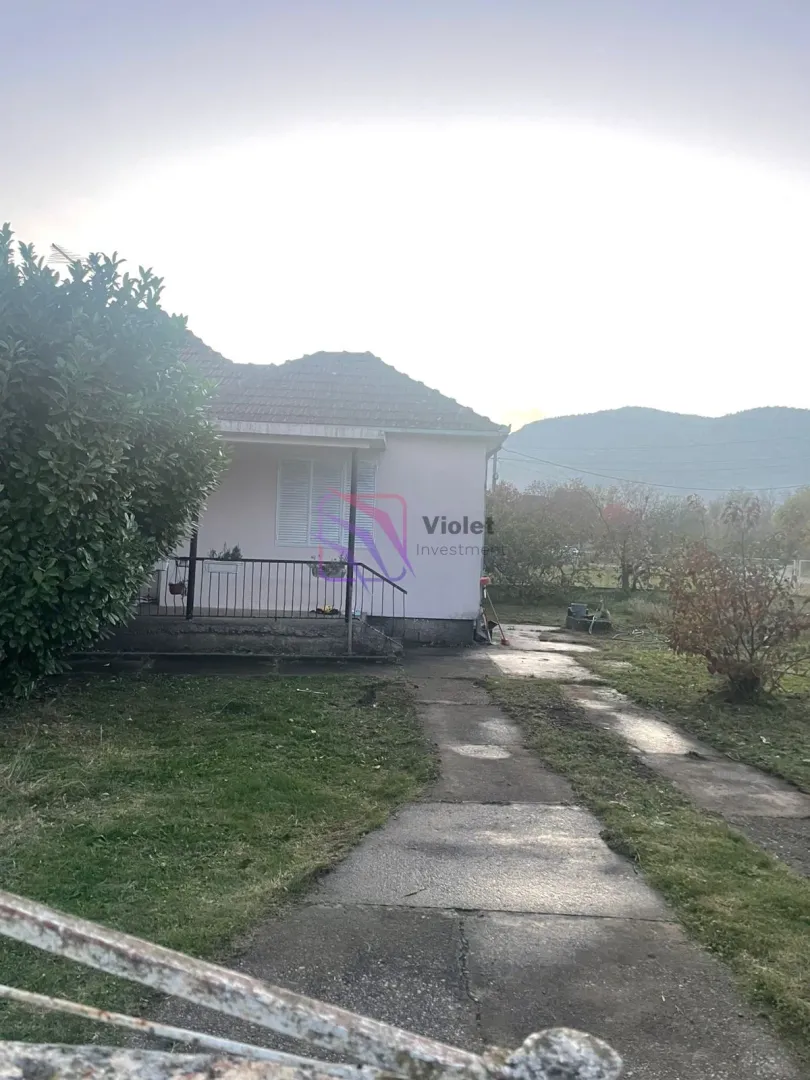 Pogled na spoljašnjost kuće sa dvorištem i stazom.