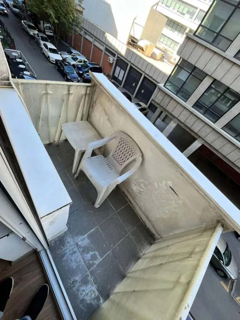Small balcony with a plastic table and chair.