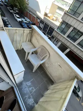 Small balcony with a plastic table and chair. - image 10
