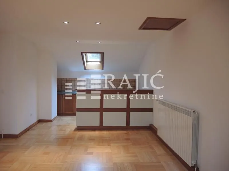 Living room with parquet flooring and a view of the kitchen with a counter.