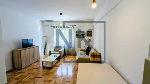 Living room with a sofa, TV unit, and parquet flooring. - image 5