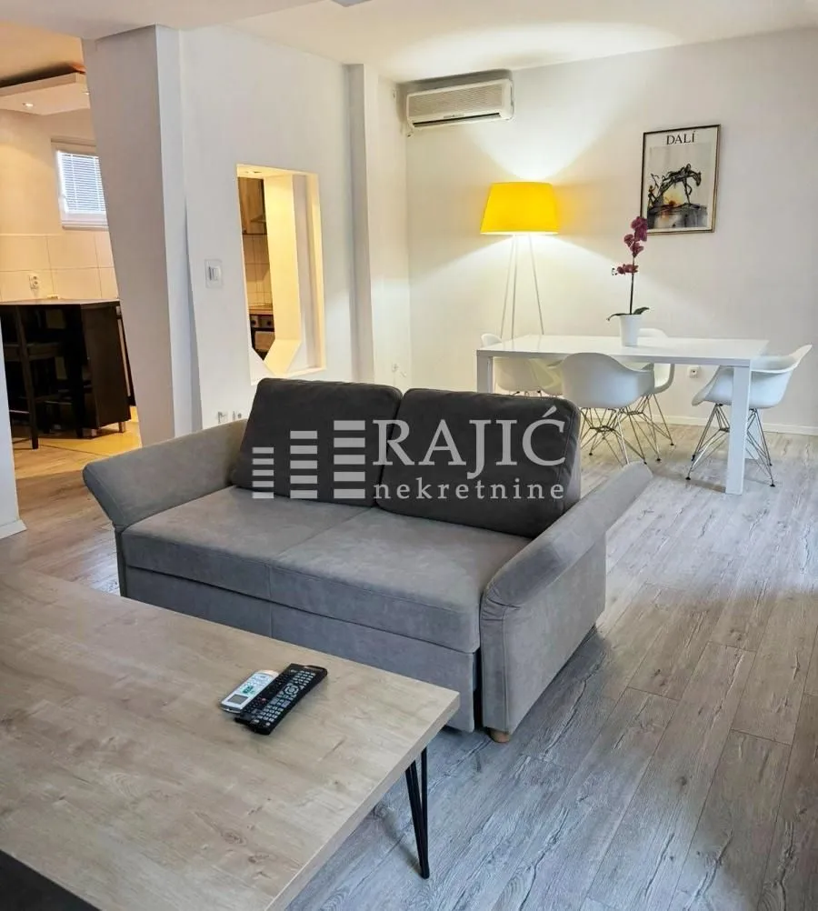 Living room with sofa and dining area in the background.