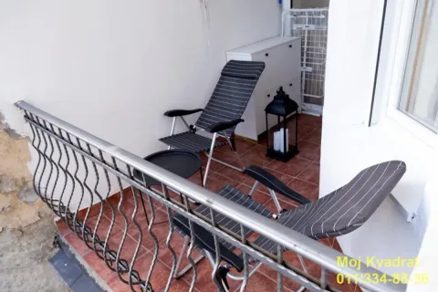 Small furnished balcony with a metal railing and seating chairs. - image 8