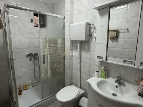 Kupatilo opremljeno tuš kabinom, umivaonikom i toaletom sa belim pločicama. - image 8
