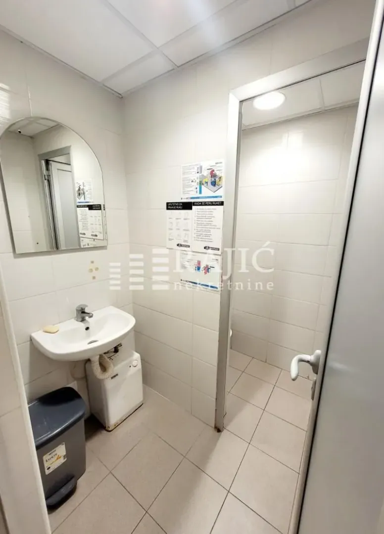 Small bathroom with a washbasin, mirror, and tiled walls.