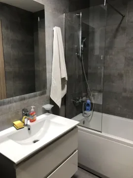 Bathroom with a bathtub and a white sink. - image 20