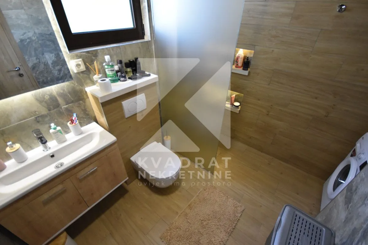 Bathroom with a washbasin, toilet, shower cabin, and washing machine.