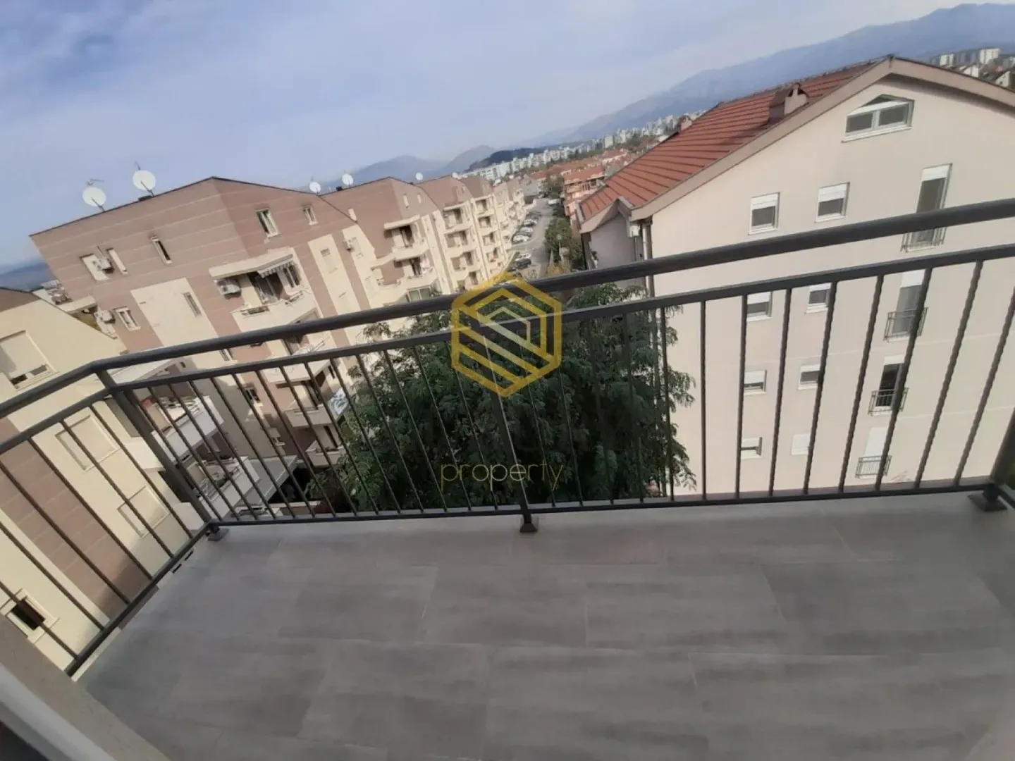 Pogled sa balkona na okolne zgrade i planine.