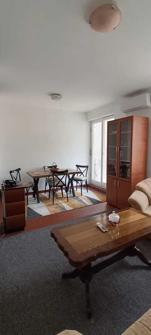Dnevni boravak sa trpezarijskim stolom, garniturom i drvenim namještajem.
