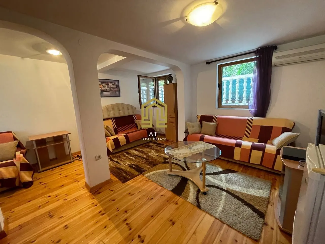 Furnished living room with sofa set and wooden floor.