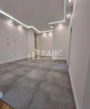 Empty room with grey floor tiles and a dropped ceiling with lighting. - image 9