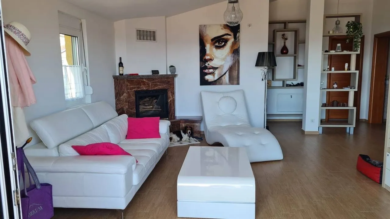 Bright living room with white furniture, fireplace, and wall art.