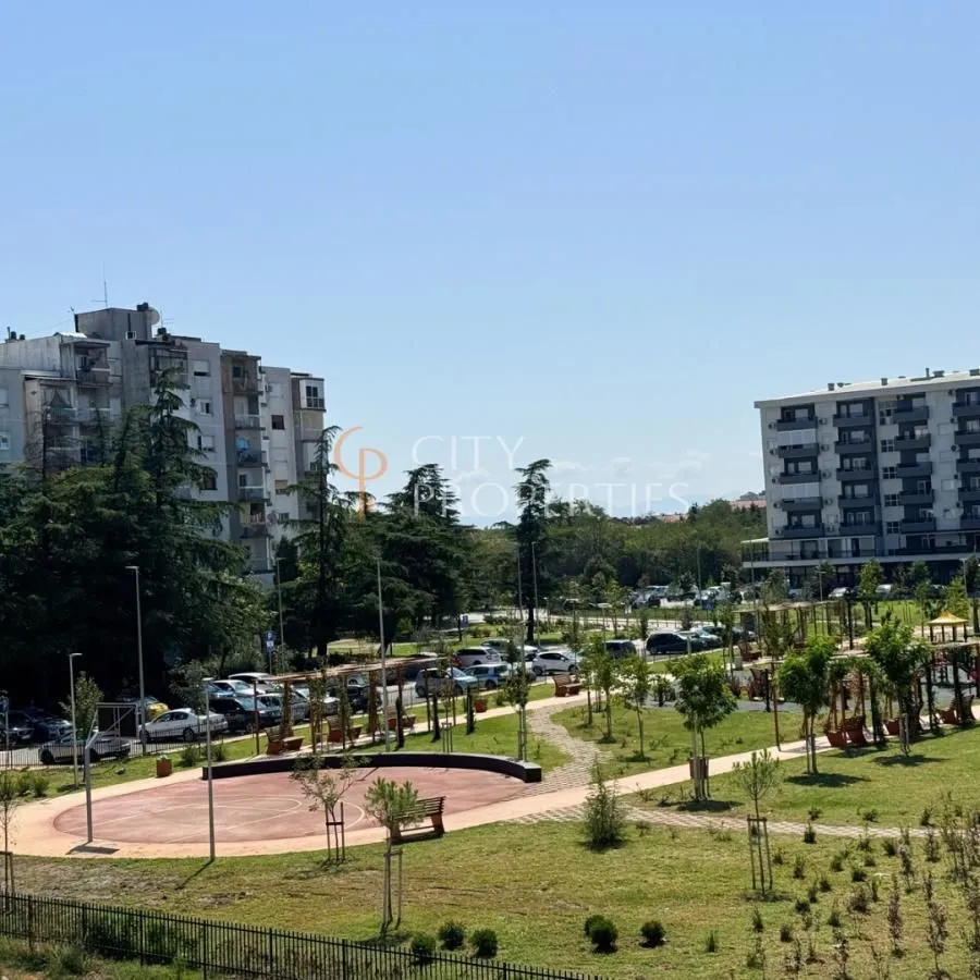 Pogled sa prozora na park i okolne stambene zgrade.