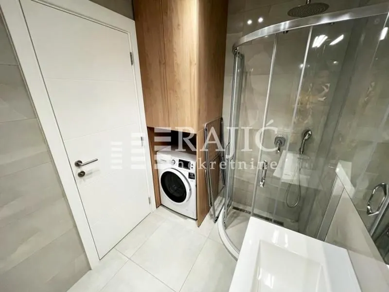 Modern bathroom equipped with a shower cabin and a built-in washing machine.