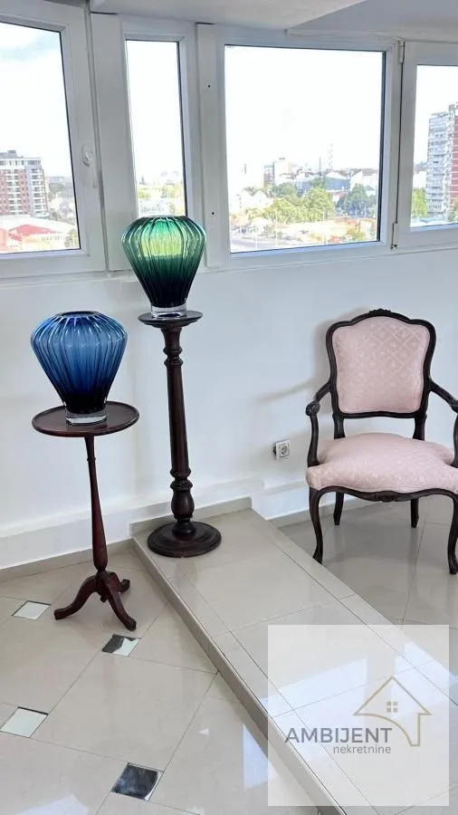 Seating corner with a classic armchair and decorative vases near the window.